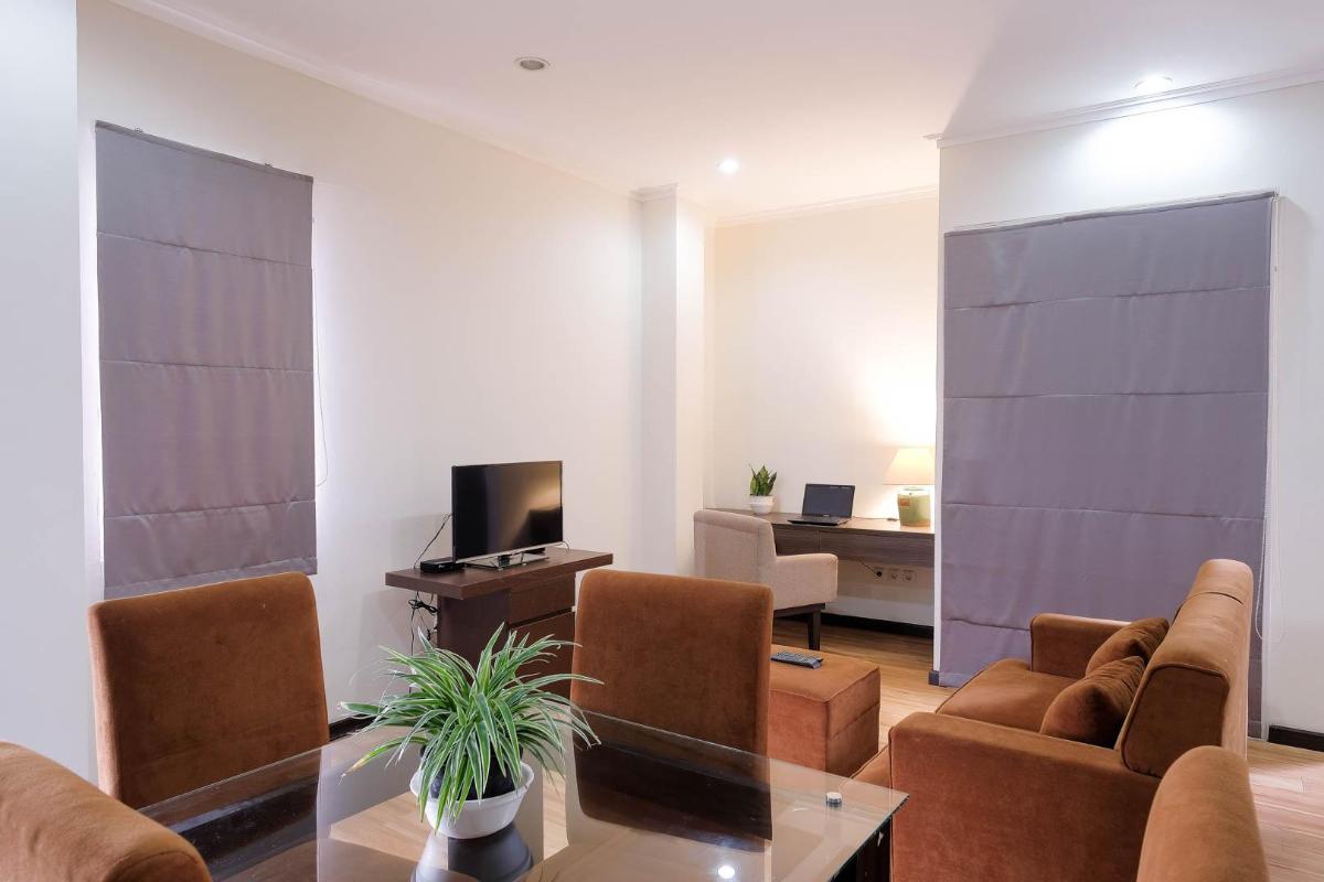 Ruang duduk Condo dengan sofa, meja makan kaca, televisi, dan meja kerja terpisah